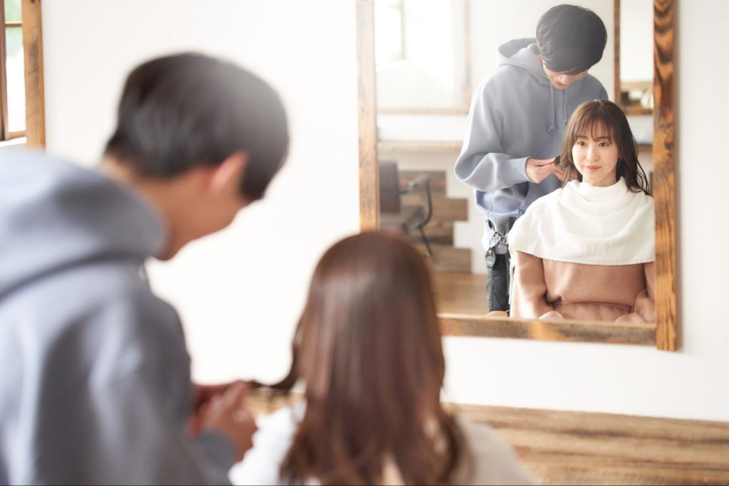 鏡にうつった美容師とお客さんの女性