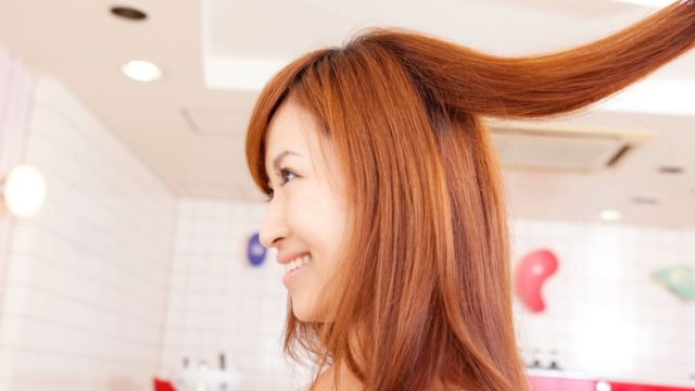 美容師に髪を持ち上げられる女性